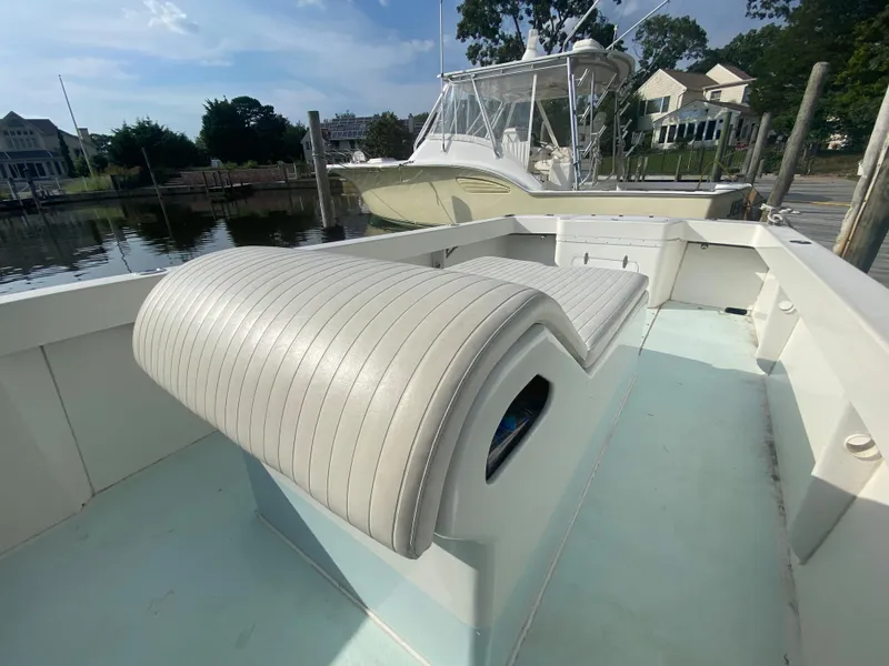 Slide: The Image of 2006 Kryptonite 41 CC boat with cushioned seating, docked near waterfront homes. - 8