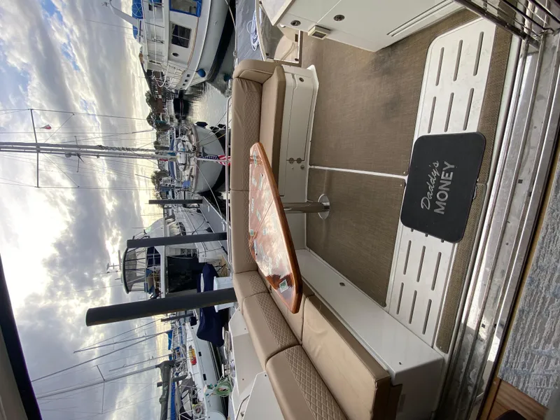 Slide: The Image of 2017 Sea Ray L590 yacht interior with seating, table, and "Daddy's Money" mat at marina. - 12