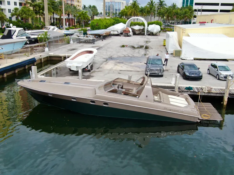 Slide: The Image of 1998 Magnum 50 Bestia yacht docked at marina, surrounded by cars and boats. - 5