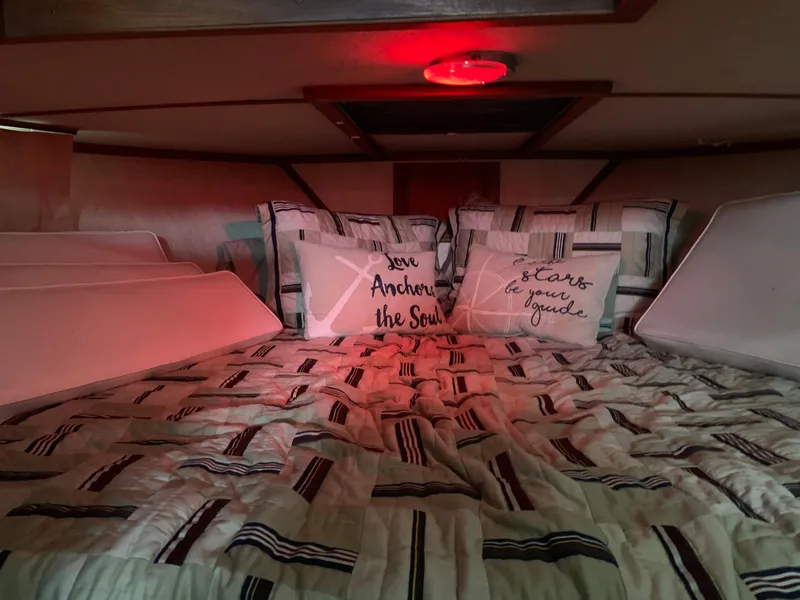 Slide: The Image of Cozy cabin bed in a 1987 Marinette Fisherman boat with nautical-themed pillows. - 18