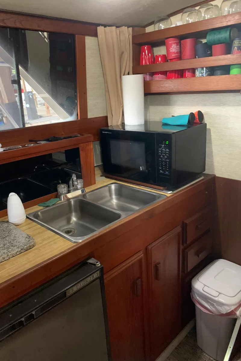 Slide: The Image of 1987 Marinette Fisherman boat kitchen with microwave, sink, and shelves. - 28