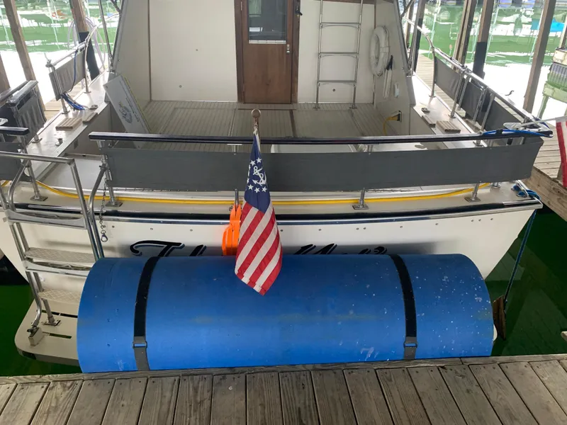 Slide: The Image of 1987 Marinette Fisherman boat docked with American flag and blue fender. - 3