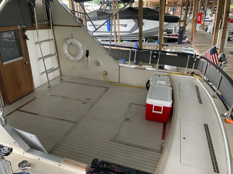 Slide: The Image of 1987 Marinette Fisherman boat deck with cooler, life ring, and docked boats in background. - 5