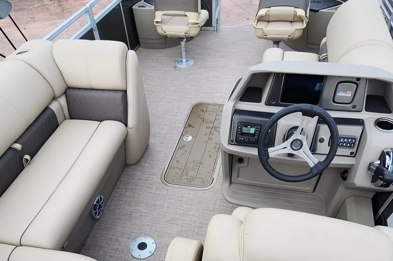 Slide: The Image of 2024 Sun Tracker Fishin' Barge 22 XP3 interior with beige seating and steering console. - 12