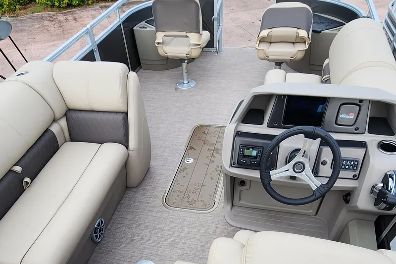 Slide: The Image of 2024 Sun Tracker Fishin' Barge 22 XP3 interior with beige seating and steering console. - 22