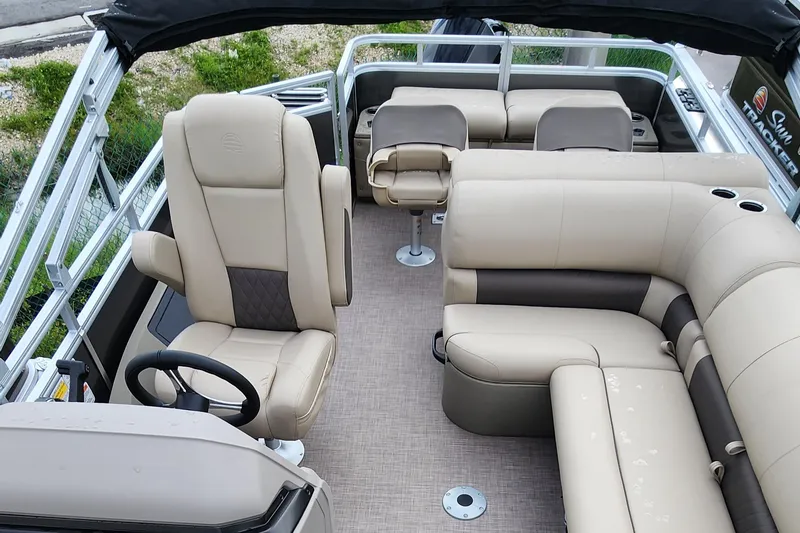 Slide: The Image of 2024 Sun Tracker Fishin' Barge 22 XP3 interior with beige seating and steering wheel. - 24