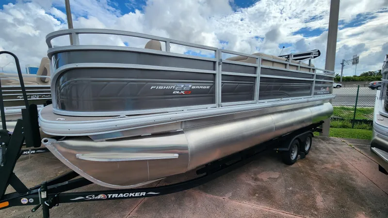 Slide: The Image of 2024 Sun Tracker Fishin' Barge 22 XP3 pontoon boat on trailer, parked outdoors. - 25