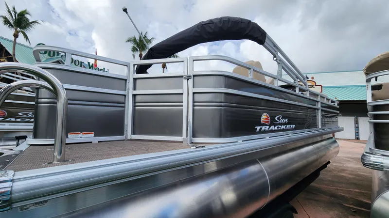 Slide: The Image of 2024 Sun Tracker Fishin' Barge 22 XP3 pontoon boat, docked under cloudy skies. - 27