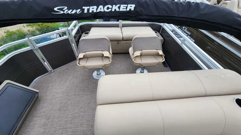 Slide: The Image of 2024 Sun Tracker Fishin' Barge 22 XP3 interior with beige seating and carpeted floor. - 29