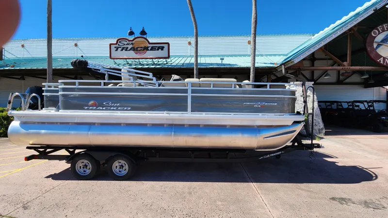Slide: The Image of 2024 Sun Tracker Fishin' Barge 22 XP3 pontoon boat on trailer outside dealership. - 3
