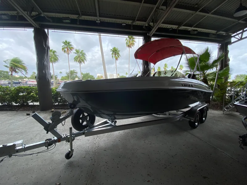 Slide: The Image of 2024 Tahoe T21 boat with red canopy on trailer under shelter. - 1