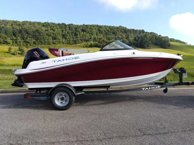 The Image of 2024 Tahoe 185 S boat on trailer, red and white, parked on road with scenic background. - 0