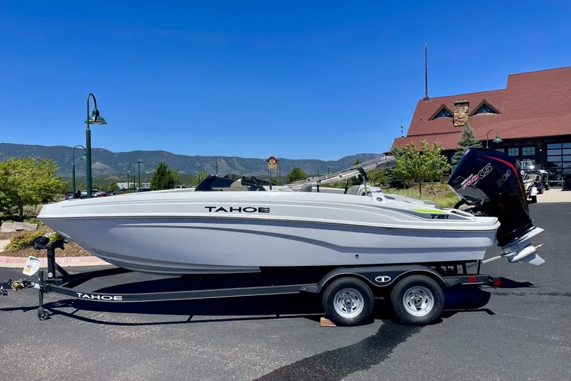 The Image of 2024 Tahoe T21 boat on trailer, parked outdoors with scenic mountain backdrop. - 0