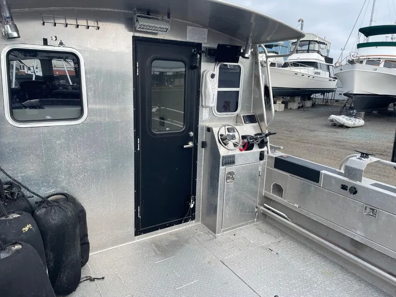 Slide: The Image of 2010 Glacier Craft Custom Aluminum boat interior with control panel and docked boats in background. - 23