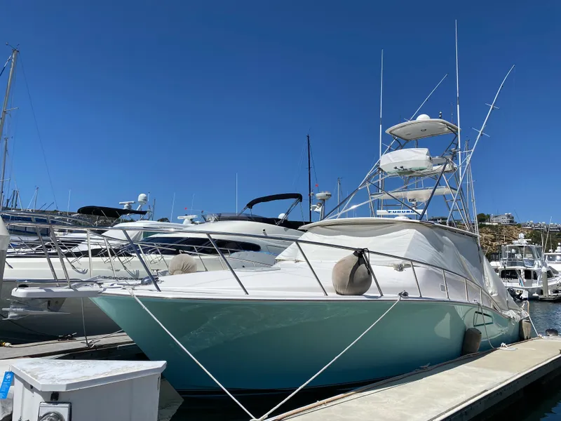 Slide: The Image of 2005 Cabo 40 Hardtop Express yacht docked in a marina under clear blue skies. - 1