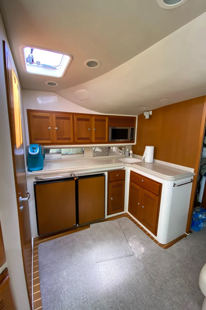 Slide: The Image of 2005 Cabo 40 Hardtop Express yacht interior kitchen with wood cabinets and modern appliances. - 38