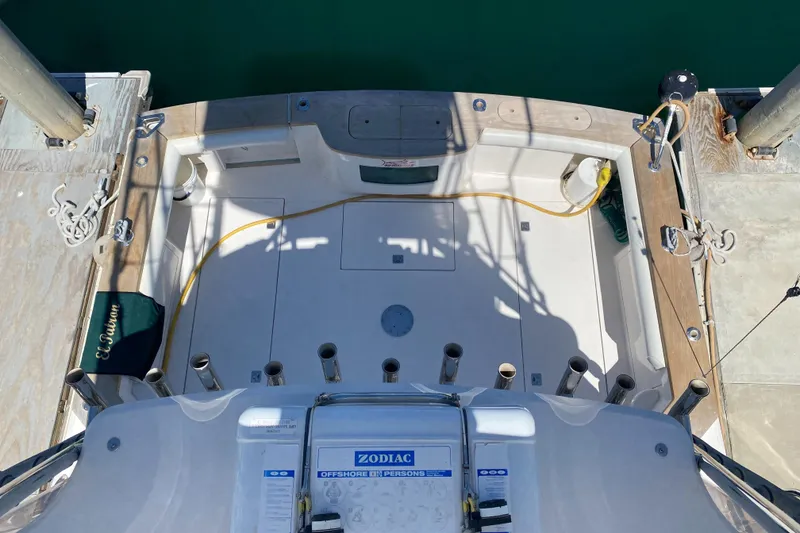 Slide: The Image of 2005 Cabo 40 Hardtop Express boat deck with fishing rod holders and docked at marina. - 6