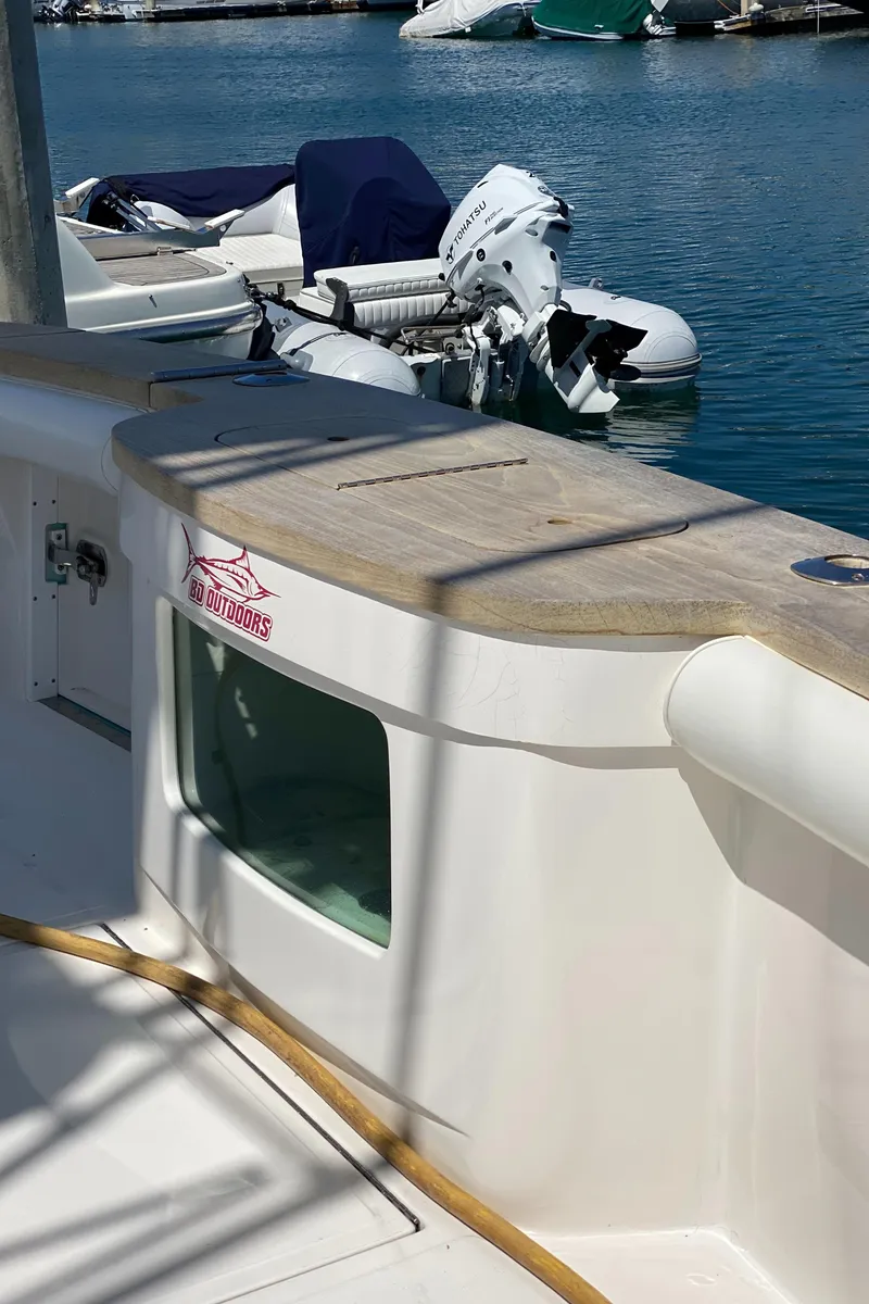 Slide: The Image of 2005 Cabo 40 Hardtop Express boat docked, featuring a wooden deck and visible outboard motor. - 8