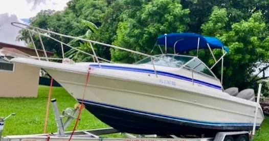 Slide: The Image of 1990 Sea Ray 240 Sundeck boat on trailer with blue canopy. - 1
