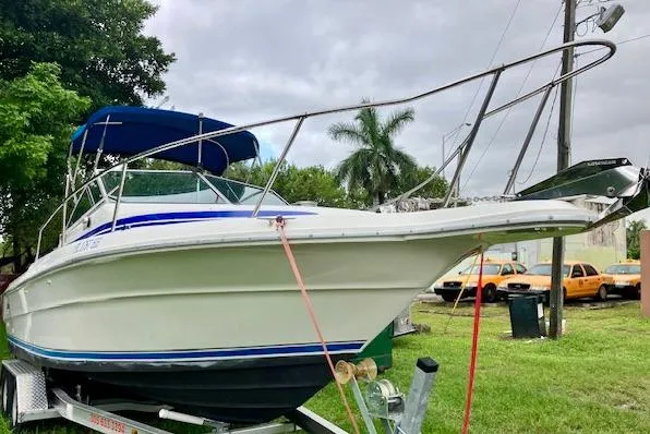Slide: The Image of 1990 Sea Ray 240 Sundeck boat on trailer, parked on grass with trees and cars in background. - 16