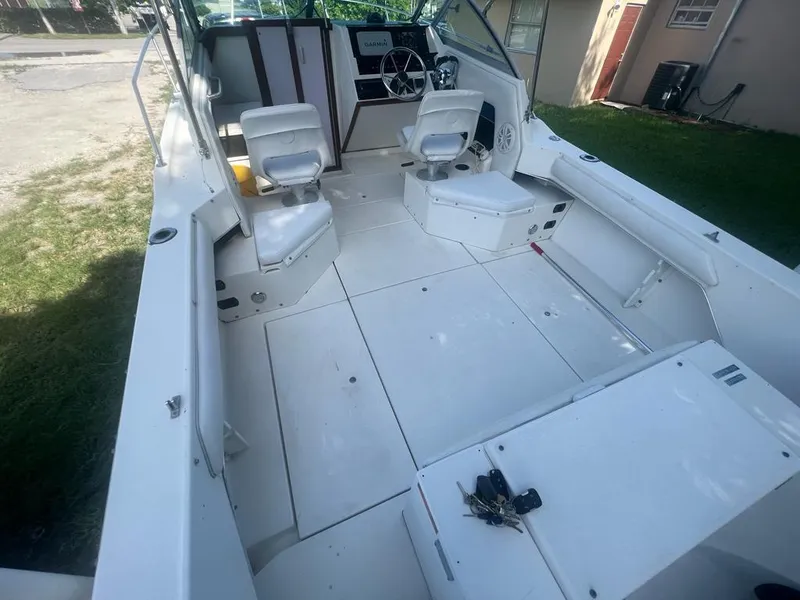 Slide: The Image of 1990 Sea Ray 240 Sundeck interior with white seating and steering wheel. - 20