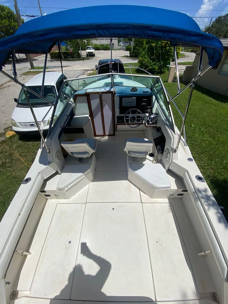Slide: The Image of 1990 Sea Ray 240 Sundeck boat with blue canopy and spacious seating area. - 21