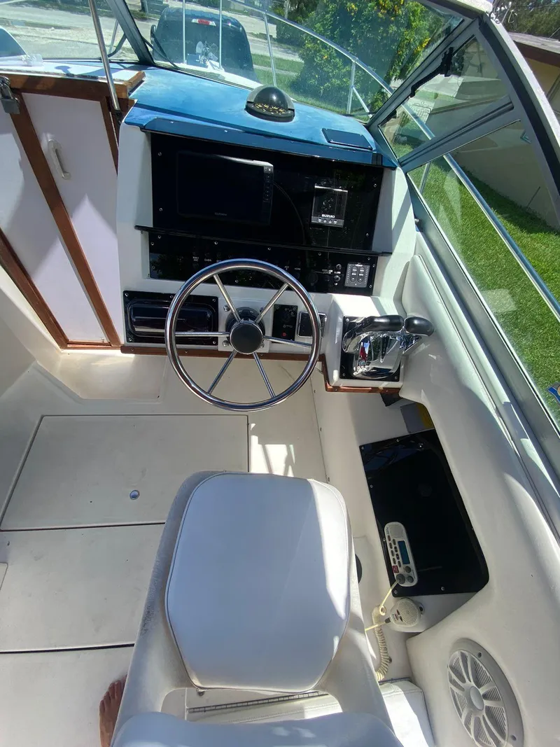 Slide: The Image of 1990 Sea Ray 240 Sundeck boat cockpit with steering wheel and control panel. - 23