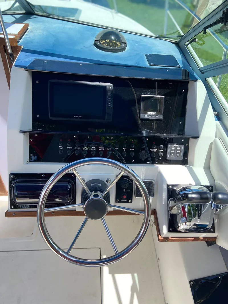 Slide: The Image of 1990 Sea Ray 240 Sundeck helm with steering wheel and control panel. - 27