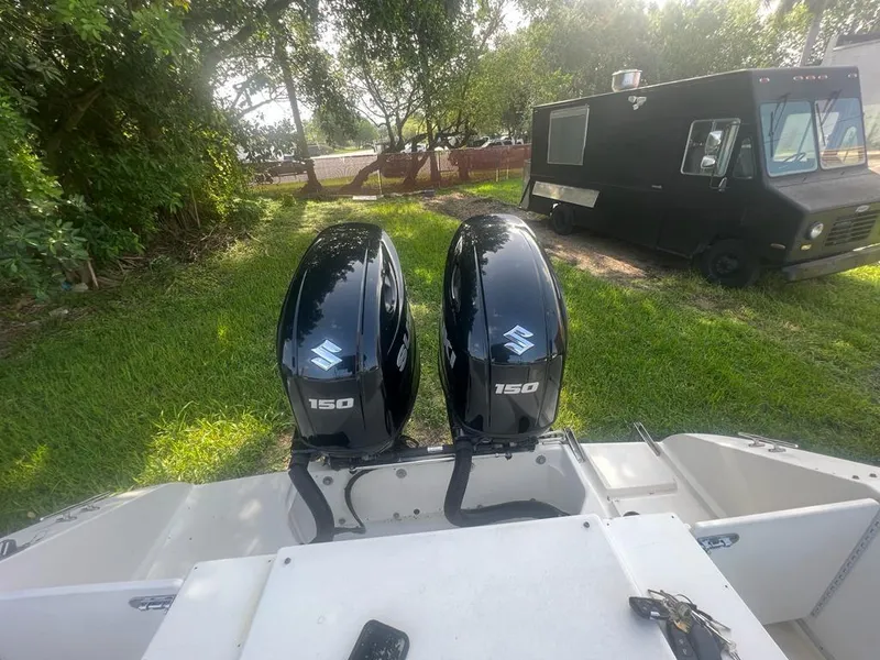 Slide: The Image of 1990 Sea Ray 240 Sundeck with twin Suzuki 150 outboard motors in grassy area. - 31