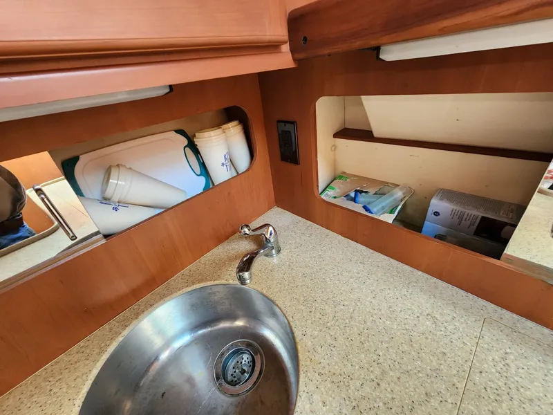 Slide: The Image of 2004 Luhrs 36 Open boat kitchen sink and countertop with storage compartments. - 37