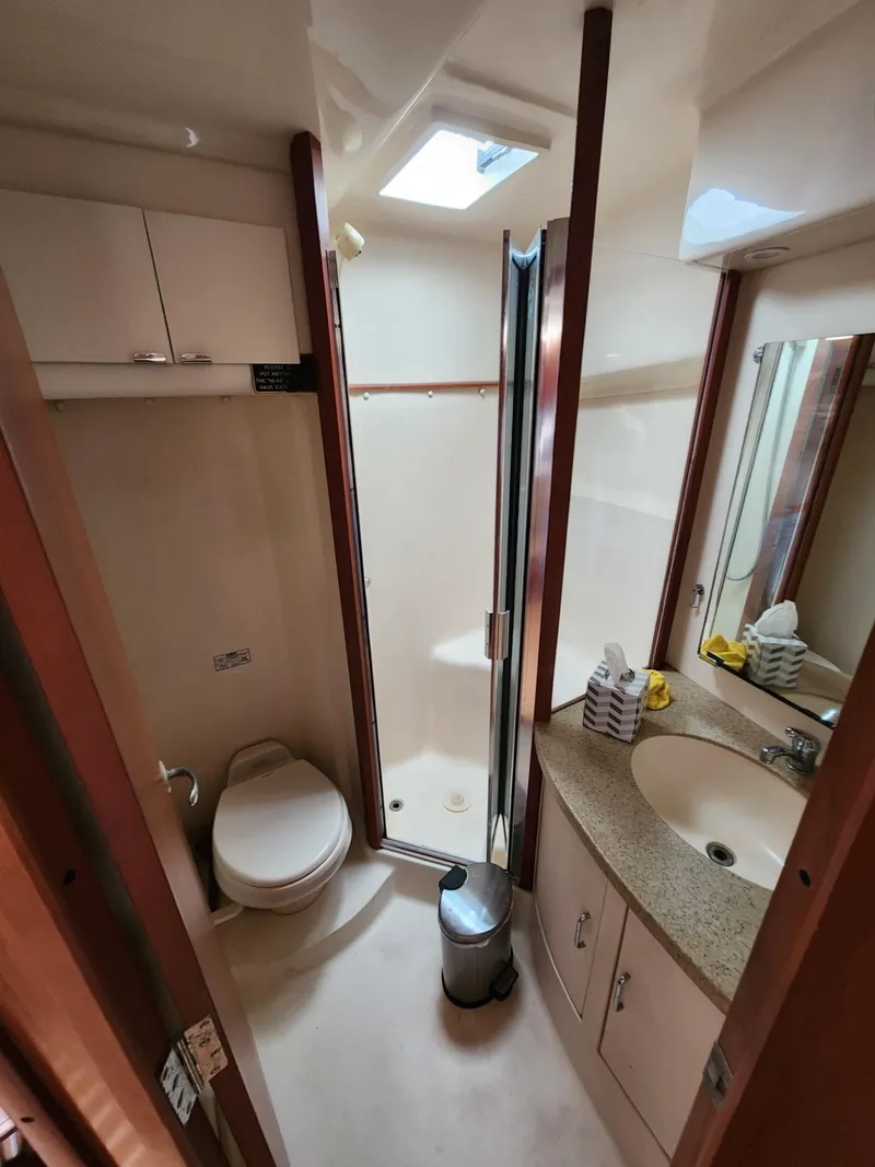 Slide: The Image of 2004 Luhrs 36 Open boat bathroom with shower, toilet, sink, and storage cabinets. - 45