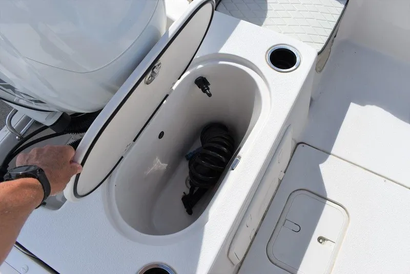 Slide: The Image of 2021 Carolina Skiff 19 LS boat storage compartment with open lid and coiled hose. - 25