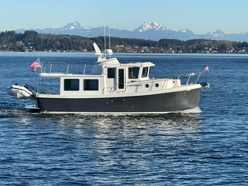 The Image of 2026 American Tug 362 cruising on a scenic waterway with mountains in the background. - 0