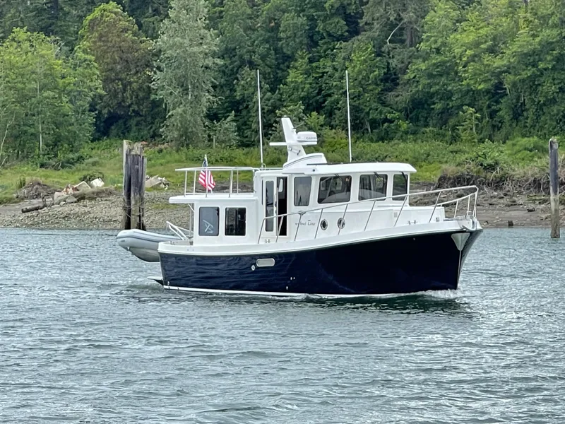 Slide: The Image of 2025 American Tug 362 cruising on a river with lush green forest in the background. - 14