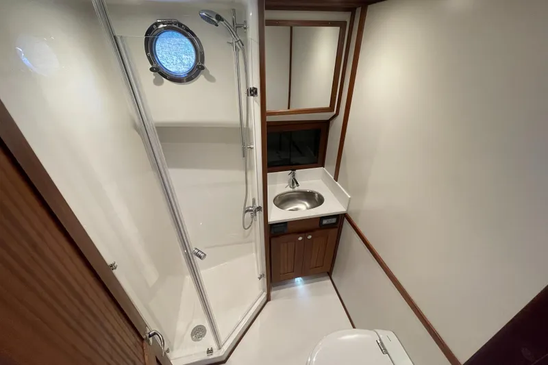 Slide: The Image of 2025 American Tug 362 bathroom with shower, sink, and porthole window. - 35