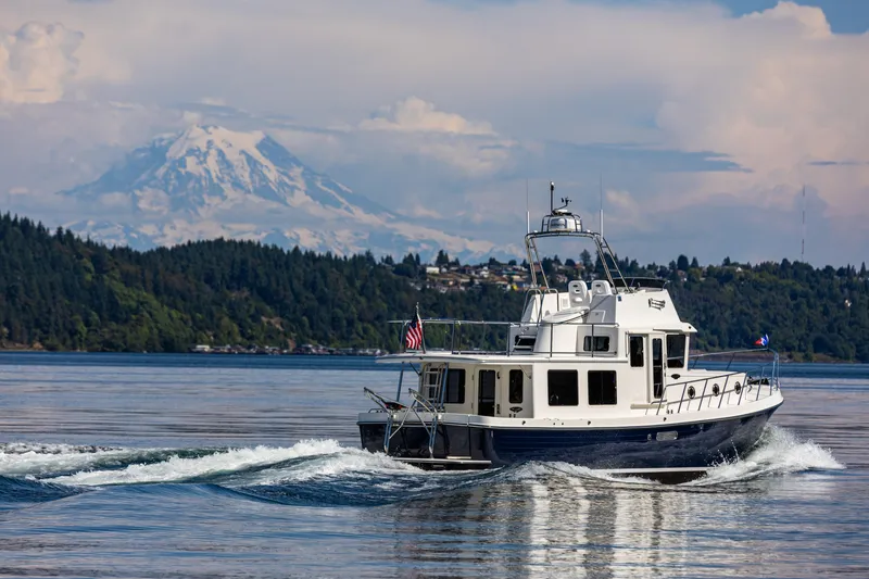 Slide: The Image of American Tug 395 (2026) cruising on a scenic lake with mountains in the background. - 2