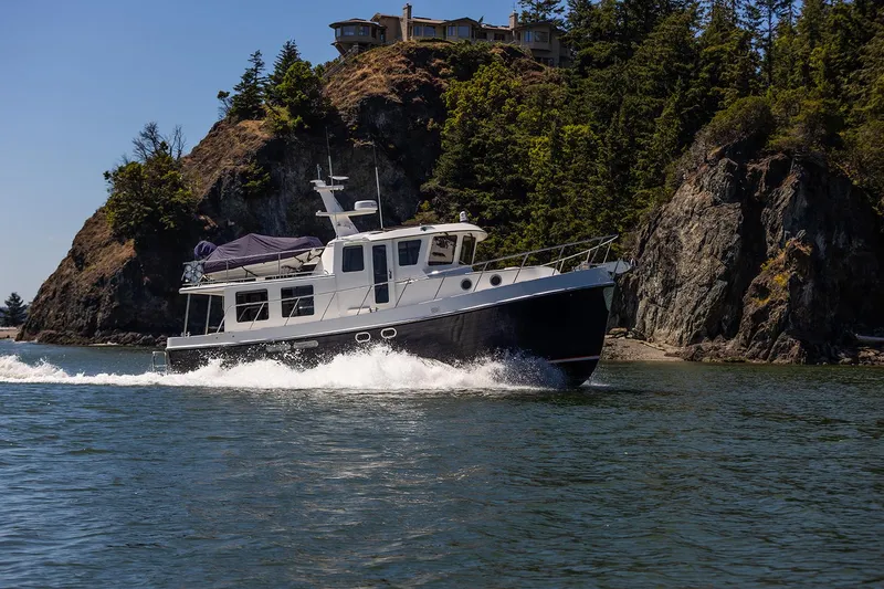 The Image of 2026 American Tug 435 cruising near rocky shoreline with trees. - 0