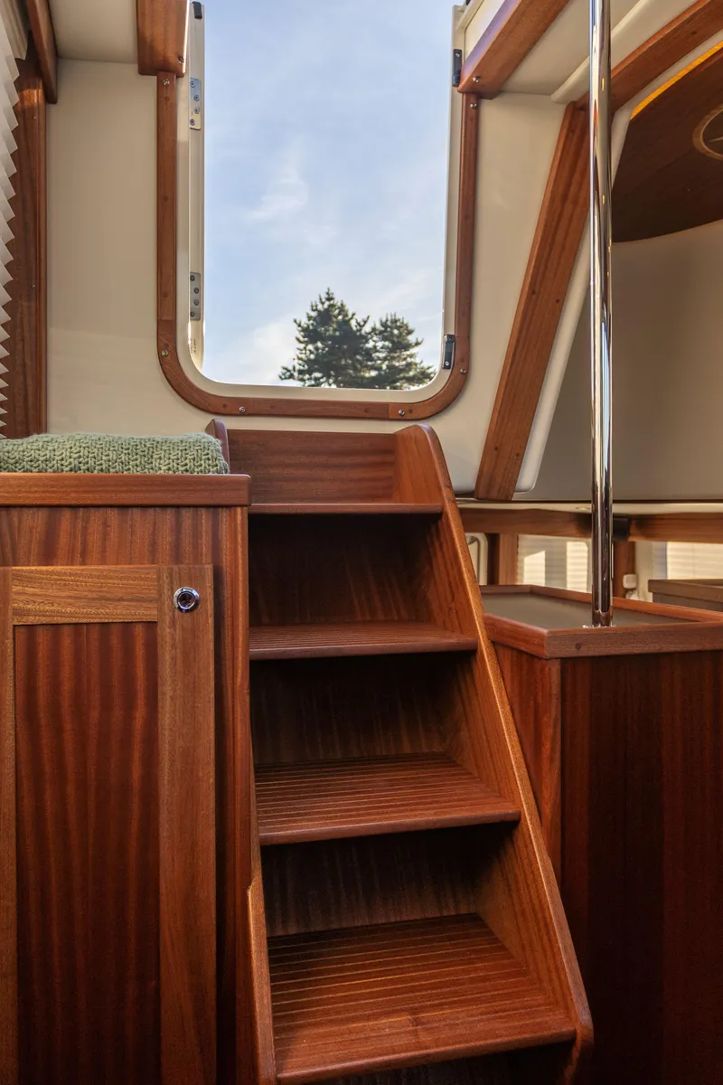 Slide: The Image of Interior wooden stairs of 2026 American Tug 435 yacht, leading to an open hatch. - 19