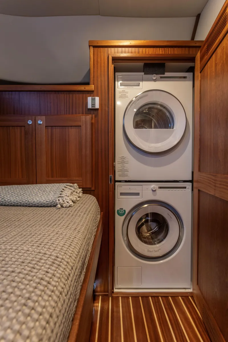 Slide: The Image of 2026 American Tug 435 interior with stacked washer and dryer beside a cozy bed. - 22