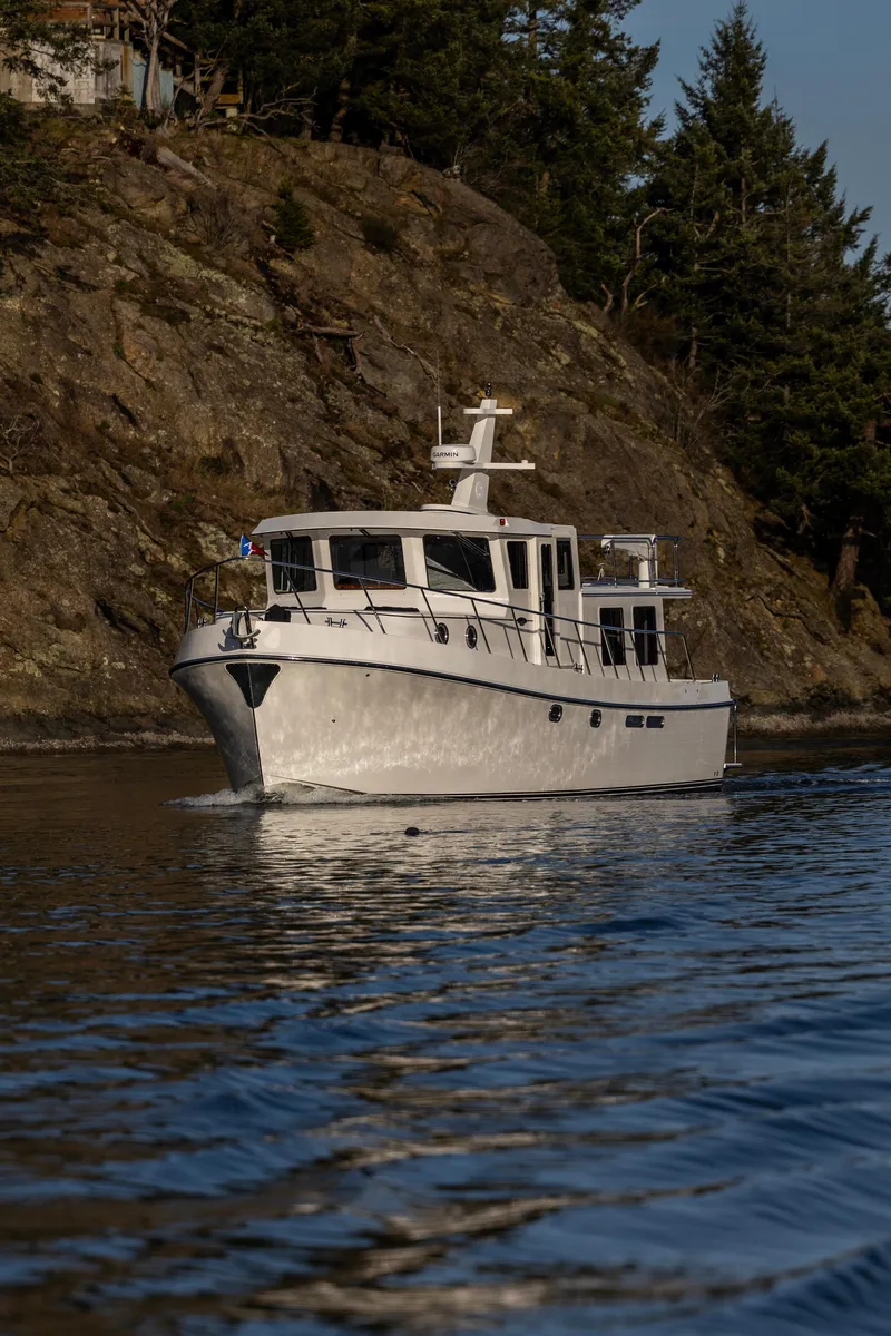 Slide: The Image of 2026 American Tug 435 cruising near rocky shoreline with trees. - 3