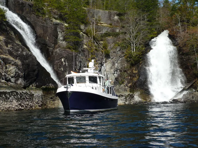 Slide: The Image of American Tug 435 (2025) cruising near scenic waterfalls and rocky cliffs. - 38