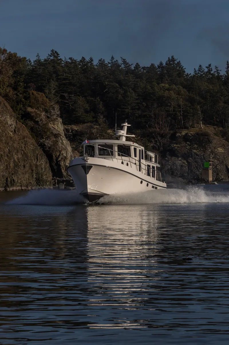 Slide: The Image of 2026 American Tug 435 cruising through scenic waters with rocky shoreline backdrop. - 4