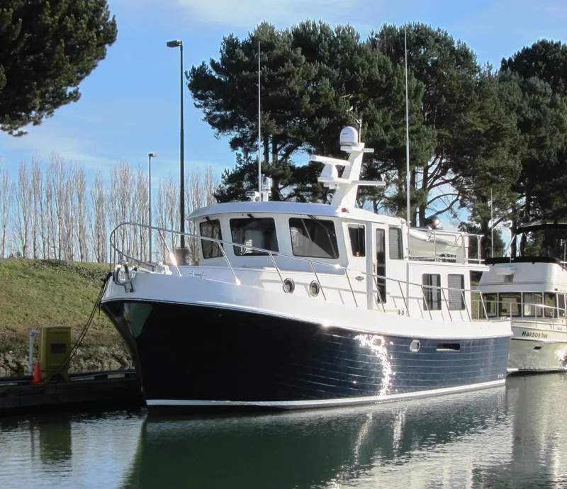Slide: The Image of American Tug 435, 2025 model, docked in a serene marina with trees in the background. - 42
