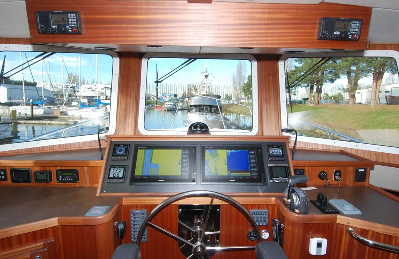 Slide: The Image of 2025 American Tug 435 helm with navigation screens and marina view. - 53