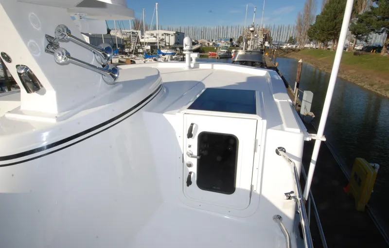 Slide: The Image of American Tug 435 (2025) deck view with hatch and marina background. - 68