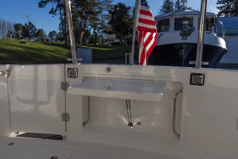 Slide: The Image of American Tug 435 (2026) deck with sink and American flag, docked near greenery. - 9