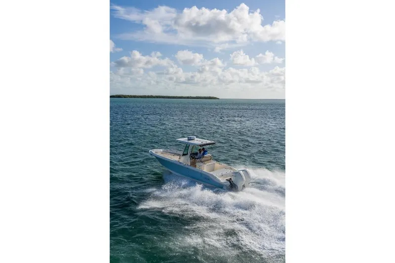 Slide: The Image of 2024 Boston Whaler 280 Dauntless cruising on open water under a partly cloudy sky. - 45