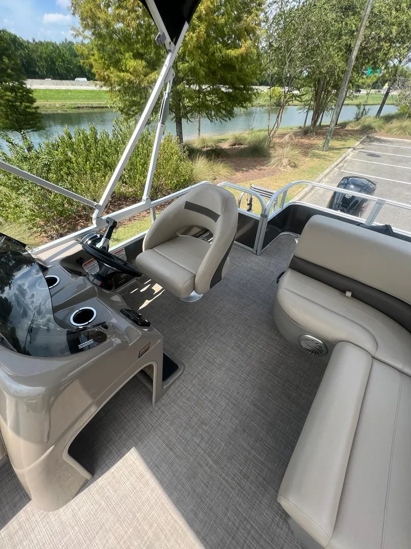 Slide: The Image of 2024 Sun Tracker Party Barge 18 DLX interior with helm, seating, and cup holders. - 14