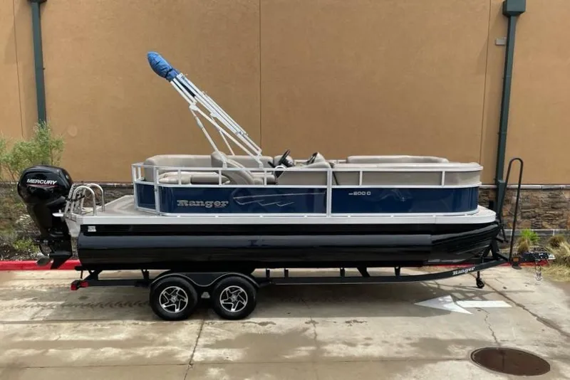 Slide: The Image of 2024 Ranger Reata 200C pontoon boat on a trailer with Mercury outboard motor. - 2