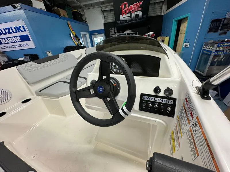 Slide: The Image of 2025 Bayliner Element M15 boat dashboard with steering wheel and control panel. - 2